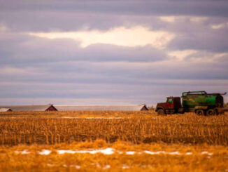 A picture of a farm truck spreading fertilizer on a field