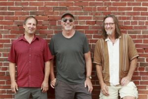 Musicians standing against a brick wall