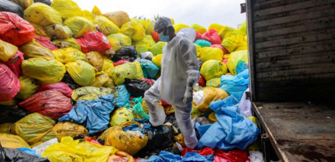 Worker assessing piles of medical waste